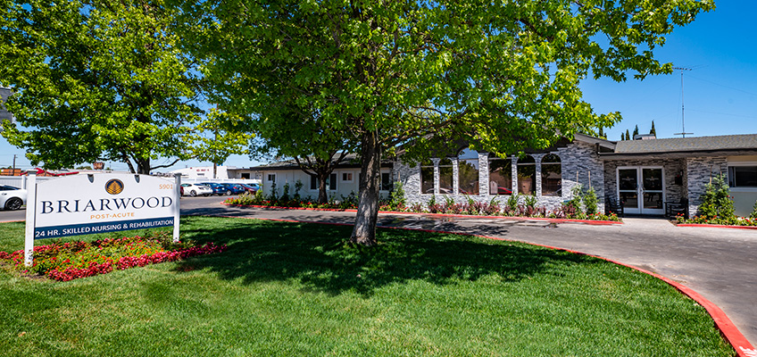briarwood-848x400-10 Lawn, bushes, and sidewalk and sign out front Briarwood Post Acute