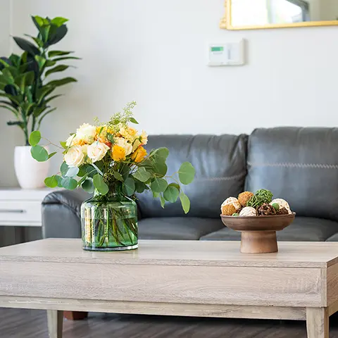 A leather couch and wooden coffee table with flowers and decor in the Sunny Hills lobby