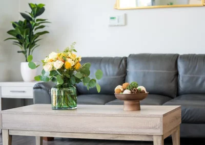 A leather couch and wooden coffee table with flowers and decor in the Sunny Hills lobby