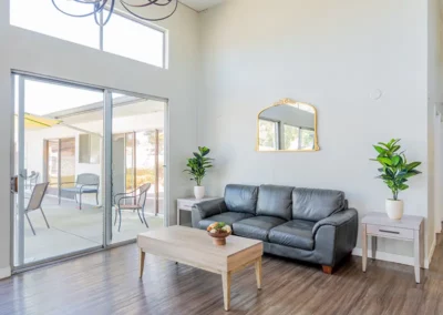 A couch and wooden coffee table in a living room with a glass door leading outside.