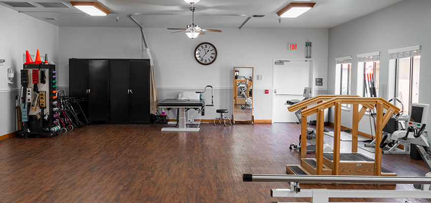 Ocean View rehab therapists and an elderly resident in the rehab gym