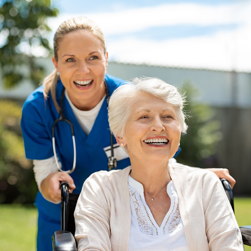 A doctor pushing an elderly woman in a wheelchair
