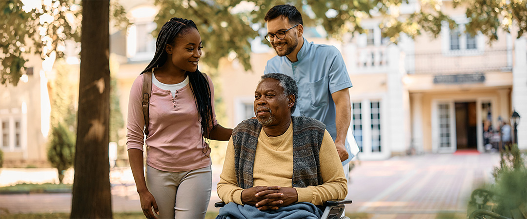 An elderly man in a wheelchair with his family members