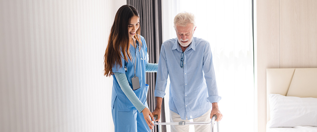 A nurse helping an elderly man with a walker