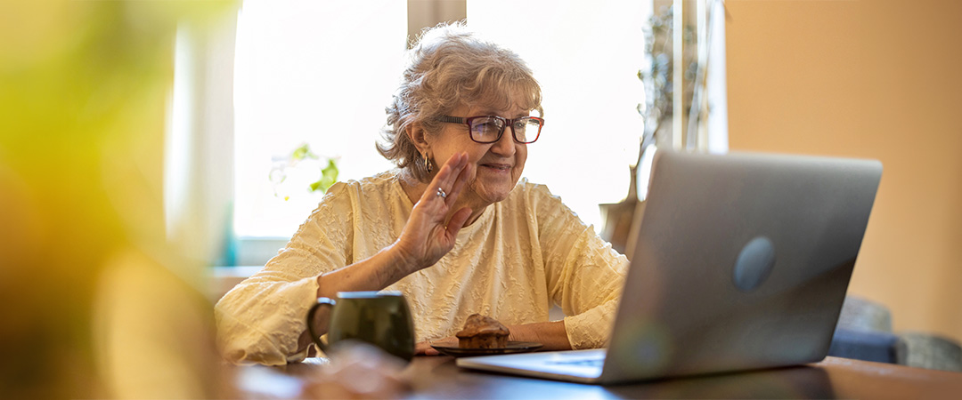 An elderly woman talking to someone on the computer