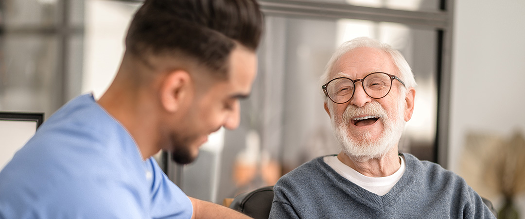 An elderly man laughing with a nurse