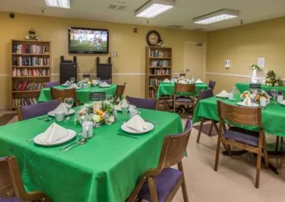 Inside dining area with tables, chairs, and bookshelves with books at the Meadows on Sunset facility