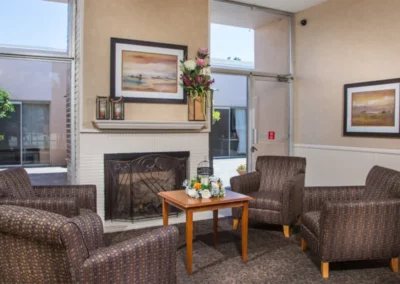 Inside the communal living area with couches, tables, and a fireplace at the Meadows on Sunset facility