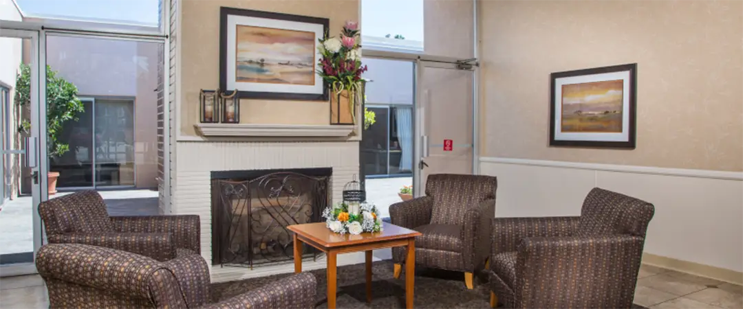 Inside the communal living area with couches, tables, and a fireplace at the Meadows on Sunset facility