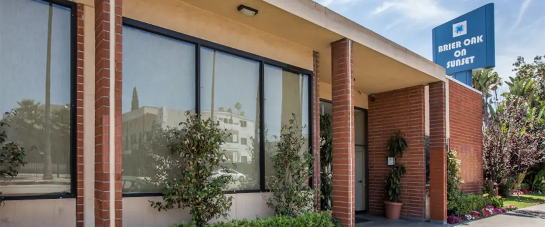 The front entrance of the Meadows on Sunset facility with a big blue sign of the facility name next to the building