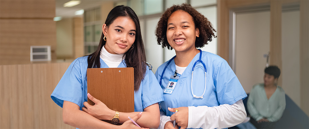 Two female healthcare workers in blue scrubs