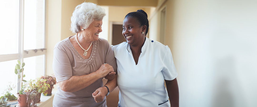 Healthcare worker and senior walking and talking
