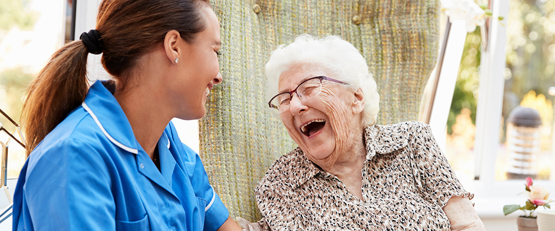 Senior woman laughing with a healthcare worker
